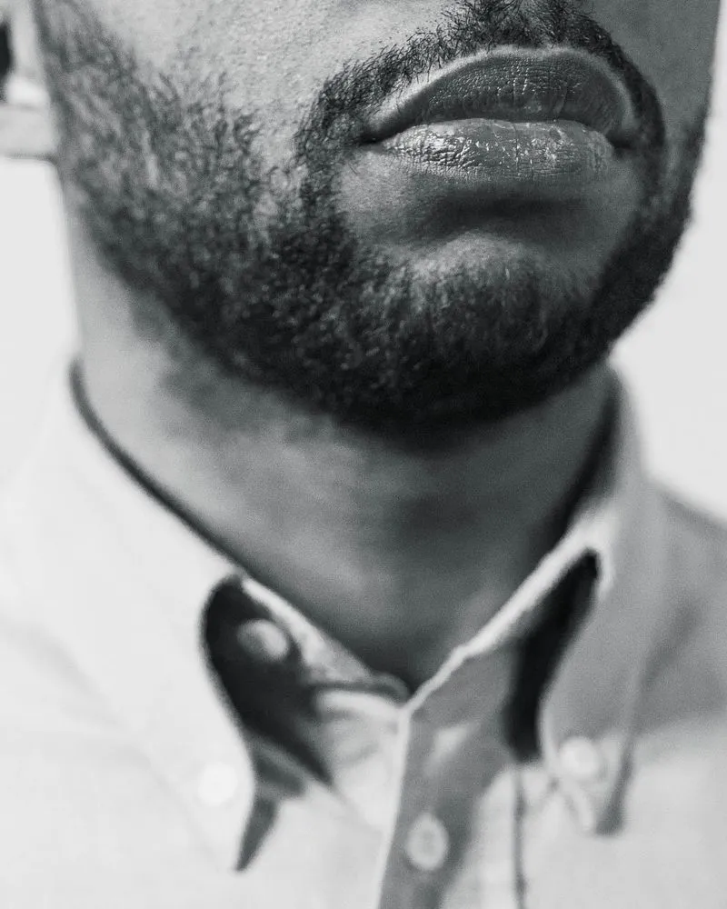 Bas du visage d'un homme barbu en chemise blanche, en noir et blanc